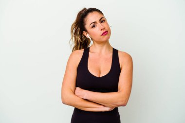 Beyaz arka planda soyutlanmış beyaz tenli, hoşnutsuzca kaşlarını çatan, kollarını kavuşturan genç bir kadın..