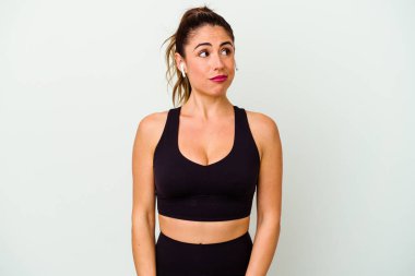 Beyaz arka planda soyutlanmış beyaz tenli genç bir kadın kafası karışmış, şüpheli ve kendinden emin değil..