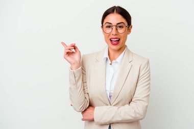 Beyaz arka planda izole edilmiş genç beyaz bir kadın işaret parmağıyla işaret ederek gülümsüyor..