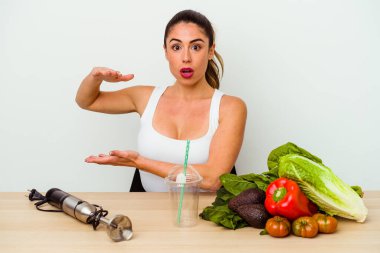 Genç beyaz kadın sebzeli sağlıklı bir smoothie hazırlıyor. Ellerinin arasında bir fotokopi alanı tutuyor..