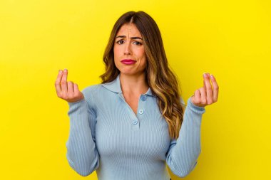 Sarı arka planda izole edilmiş genç beyaz kadın parasız olduğunu gösteriyor..