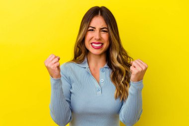 Sarı arka planda izole edilmiş genç beyaz kadın gergin elleriyle çığlık atıyor..