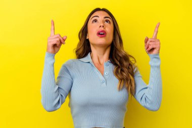 Sarı arka planda izole edilmiş beyaz bir kadın ağzı açık bir şekilde üst tarafı işaret ediyor..