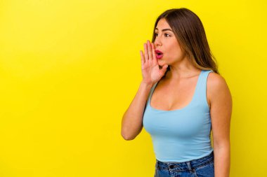 Sarı arka planda izole edilmiş genç beyaz kadın gizli bir sıcak fren haberi veriyor ve yana bakıyor.