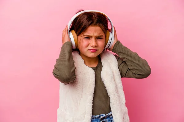 Маленькая Кавказская Девочка Слушает Музыку Изолированную Розовом Фоне Закрывая Уши — стоковое фото