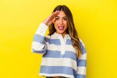 Sarı arka planda izole edilmiş genç beyaz kadın yüksek sesle bağırıyor, gözleri açık ve elleri gergin tutuyor..