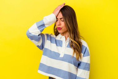 Sarı arka planda izole edilmiş genç beyaz kadın bir şeyi unutuyor. Alnına avuç içi ve kapalı gözlerle vuruyor..