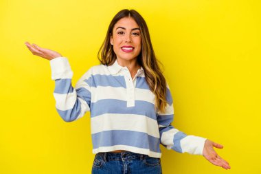 Sarı arka planda izole edilmiş genç, beyaz bir kadın. Kafası karışmış ve omuz silkiyor. Kopya alanını tutmak için..