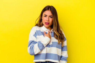 Sarı arka planda izole edilmiş genç beyaz kadın parmağını göstererek şaşırdı, geniş bir gülümsemeyle..