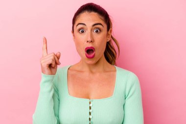 Pembe arka planda izole edilmiş genç beyaz kadın gülümseyerek beş numarayı parmaklarıyla gösteriyor..