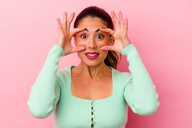 Pembe arka planda izole edilmiş genç beyaz kadın alaycı bir ifadeyle kameraya bakıyor..