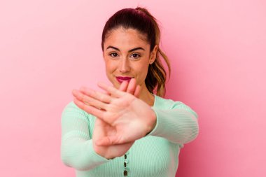 Pembe arka plan noktalarında izole edilmiş genç beyaz kadın iki seçenek arasında seçim yapmaya çalışıyor..