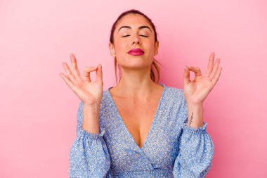 Pembe arka planda izole edilmiş genç beyaz kadın esniyor. Ağzı eliyle kapatan yorgun bir hareket sergiliyor..