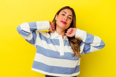 Sarı arka planda izole edilmiş, kollarını uzatan, rahat bir pozisyonda genç beyaz bir kadın..