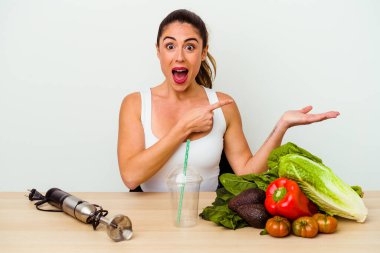 Genç, beyaz bir kadın sebzeli sağlıklı bir smoothie hazırlıyor. Elinde bir fotokopi odası var..