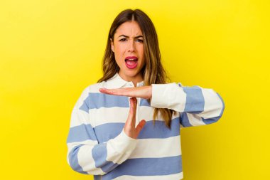 Sarı arka planda izole edilmiş genç beyaz kadın bir mola hareketi gösteriyor..