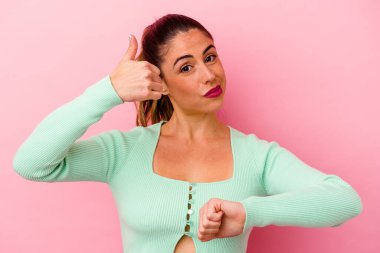 Pembe arka planda izole edilmiş genç beyaz kadın parmaklarıyla taş hareketi gösteriyor.