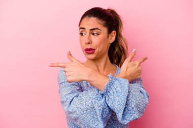 Pembe arka planda izole edilmiş genç beyaz kadın bir başarı fırsatı bulmak için gözlerini açık tutuyor..