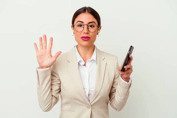白い背景に孤立した携帯電話を持っている若いビジネス女性は指で5番目を示す陽気に笑って — ストック写真