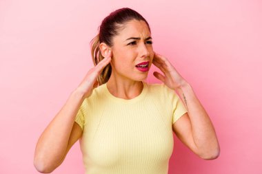 Pembe arka planda izole edilmiş genç beyaz kadın yemin ediyor, elini göğsüne koyuyor..