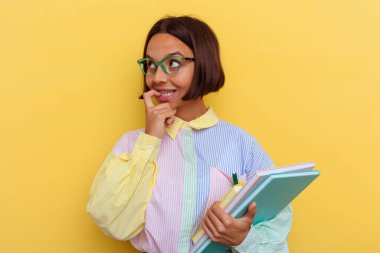 Sarı arka planda izole edilmiş genç bir ırk öğrencisi. Bir şeyin fotokopi odasına baktığını düşünerek rahatlamış..