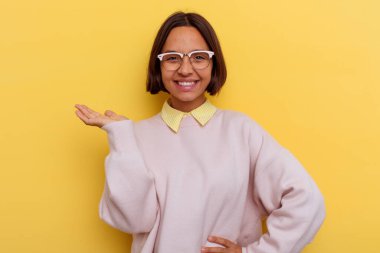 Sarı arka planda izole edilmiş genç öğrenci ırk kadını bir avuç içinde fotokopi alanı ve belinde bir el daha gösteriyor..