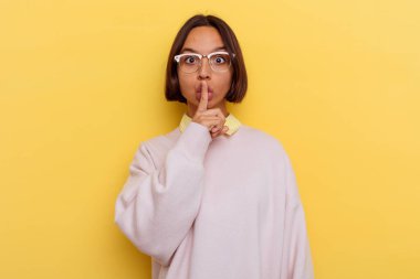Genç öğrenci melez kadın sarı arka planda izole edilmiş ya sır saklıyor ya da sessizlik istiyor..