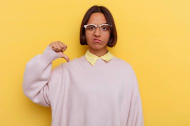 Sarı arka planda izole edilmiş, hoşlanmadığı bir hareket gösteren genç, melez bir kız öğrenci. Anlaşmazlık konsepti.