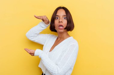 Sarı arka planda izole edilmiş genç bir ırk kadını elleri arasında bir kopya alanı tutarken şok ve şaşkınlık yaşadı..