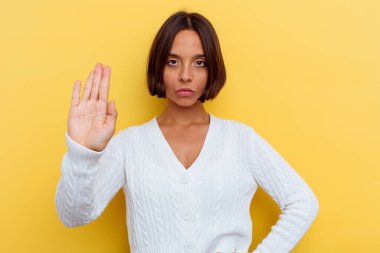 Sarı arka planda izole edilmiş genç, melez bir kadın elini uzatmış, dur işareti göstererek seni engelliyor..