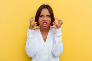 Sarı arka planda izole edilmiş genç melez kadın gergin ellerle çığlık atıyor..