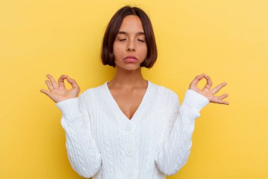 Sarı arka planda soyutlanmış genç melez kadın sıkı çalışma gününden sonra rahatlıyor, yoga yapıyor..