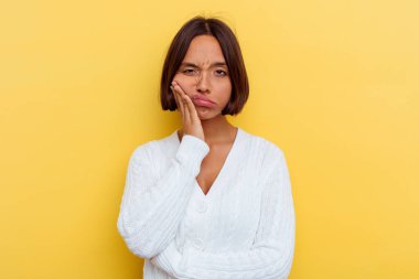 Sarı arka planda soyutlanmış, sıkılmış, yorgun ve dinlenmeye ihtiyacı olan genç melez bir kadın..