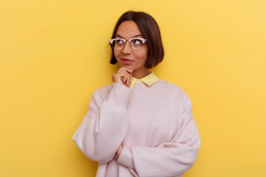 Sarı arka planda izole edilmiş, kuşkulu bir ifadeyle yan bakan genç bir ırk öğrencisi..