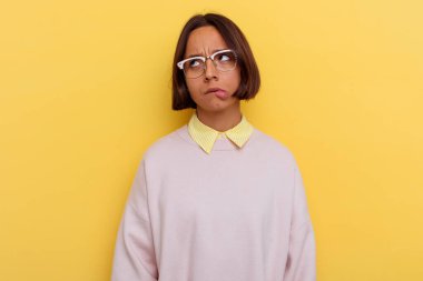 Sarı arka planda izole edilmiş genç bir öğrenci. Kafası karışmış, kararsız ve kendinden emin değil..