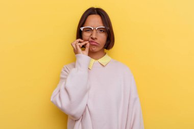 Sarı arka planda izole edilmiş, dudakları dudaklarında sır saklayan genç bir ırk öğrencisi..