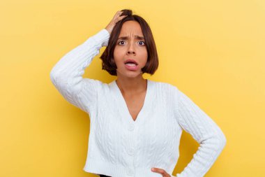 Sarı arka planda soyutlanmış genç melez bir kadın yorgun ve uykulu bir şekilde ellerini başının üstünde tutuyor..