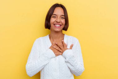 Sarı arka planda soyutlanmış genç bir ırk kadını gülüyor, ellerini kalbe koyuyor, mutluluk kavramını koruyor..