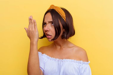 Sarı arka planda izole edilmiş genç bir ırk kadını bir şeyi unutuyor, alnına avuç içi ile vuruyor ve gözlerini kapatıyor..