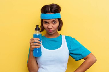 Genç spor melezi kadın izole edilmiş sarı arka planda enerji içeceği içiyor.