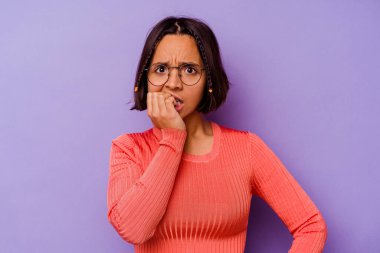 Mor arka planda izole edilmiş, tırnak yiyen, gergin ve endişeli genç bir ırk kadını..