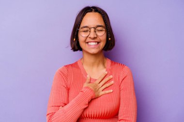 Mor arka planda soyutlanmış genç bir ırk kadını yüksek sesle gülüyor ve elini göğsüne koyuyor..