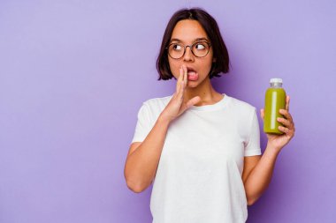 Mor arka planda izole edilmiş sağlıklı bir smoothie tutan genç melez kadın gizli bir fren haberinin olduğunu söylüyor.