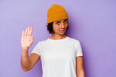 Mor arka planda yünlü şapka takan genç bir ırk kadını elini uzatıp dur işareti göstererek seni engelliyor..