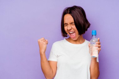 Mor arka planda izole edilmiş su şişesi tutan genç melez bir ırk zaferden sonra yumruğunu kaldırıyor, kazanan konsept..