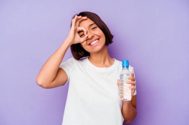 Mor arka planda izole edilmiş su şişesi tutan genç melez..