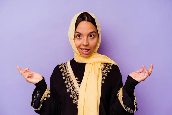紫の背景に隔離された典型的なアラビア語の衣装を身に着けている若いアラブの女性は驚きとショックを受けた — ストック写真