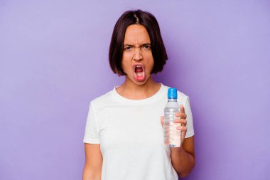 Mor arka planda izole edilmiş su şişesini tutan genç melez ırk çok sinirli ve agresif bağırıyor..