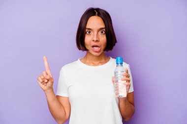 Mor arka planda izole edilmiş su şişesi tutan genç melez bir ırk. Harika bir fikir, yaratıcılık kavramı var..