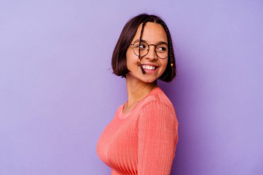 Mor arka planda soyutlanmış genç melez bir kadın. Gülümsüyor, neşeli ve keyifli görünüyor..